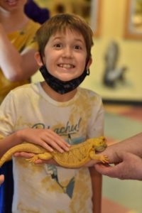 Tanner smiling while petting a lizard during SEE camp