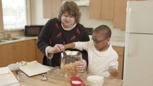 Kim helping a student cook during an activity