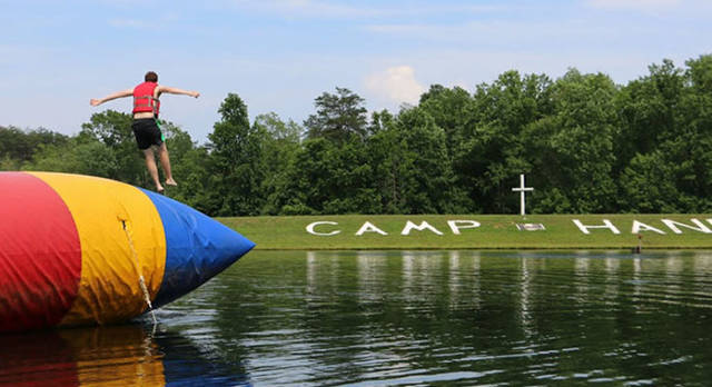 boy jumps off blob into lake at camp hanes