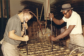 Two men work together to assemble box springs.