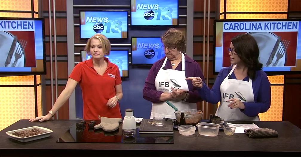 3 females on newsroom set preparing brownies.
