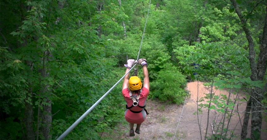 Kid who is blind rides down a zipline through the forest