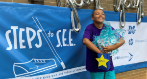 participant stands in front of a Steps to S.E.E. banner
