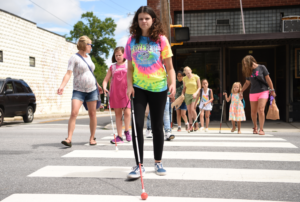 girl with cane crosses road