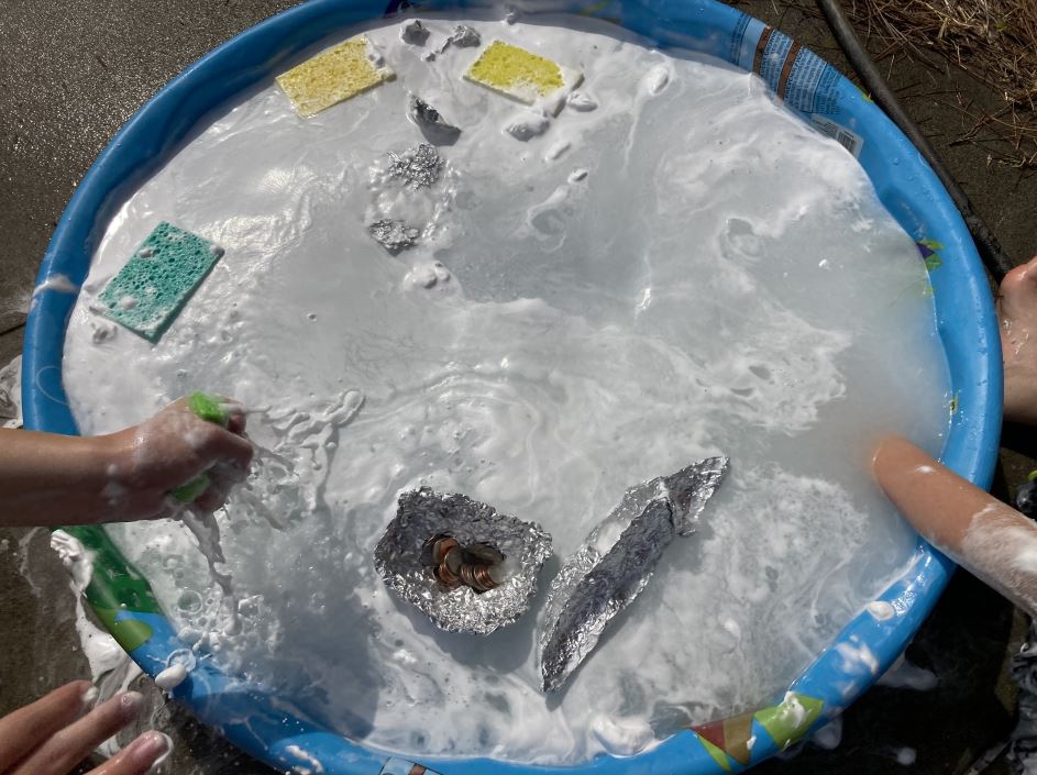 Image of kiddie pool with soapy water and hands reaching in