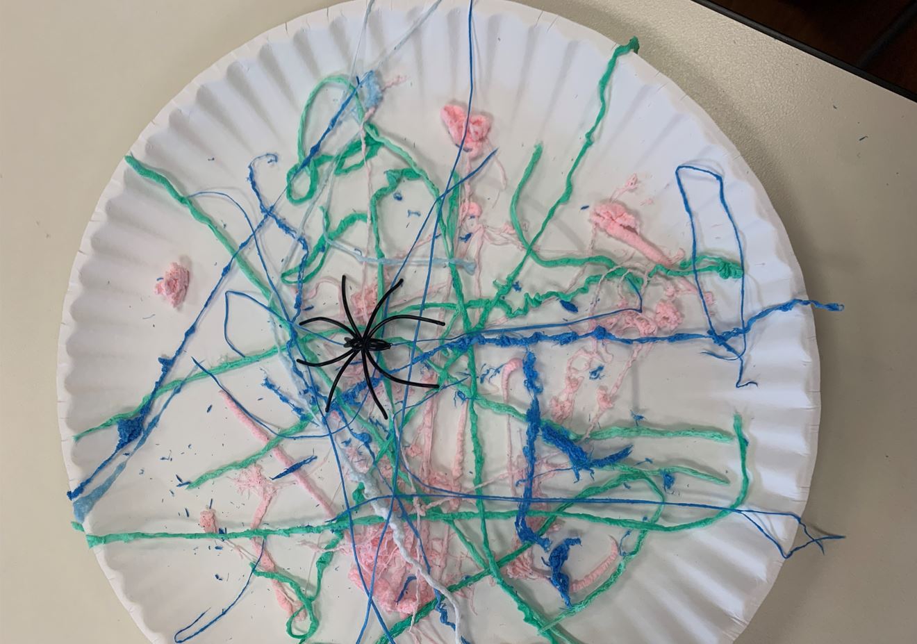 Silly string on a paper plate with a plastic spider in the center