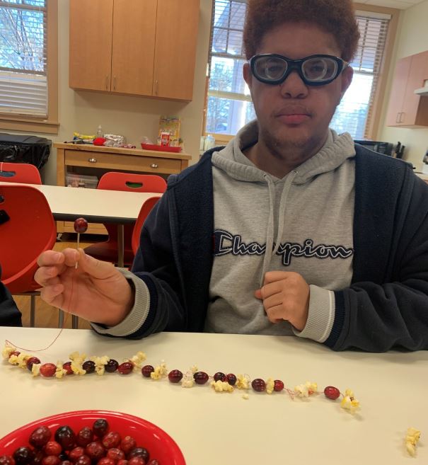SEE student with work-in-progress cranberry and popcorn garland