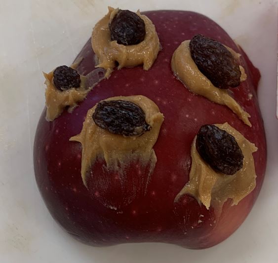 half an apple with raisins stuck on it with peanut butter