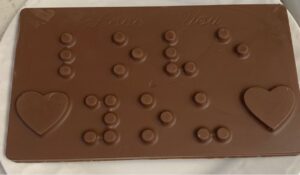 is Braille Chocolate Bar that says “Love You” with Hearts on the bottom right and left corners