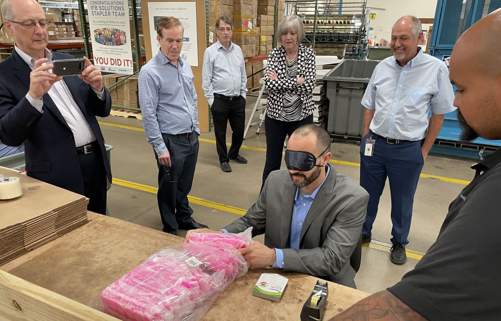 Ramon Barreto with the Commission assembling ice cube trays while blindfolded to understand the value of labor our employees who are blind add to each product