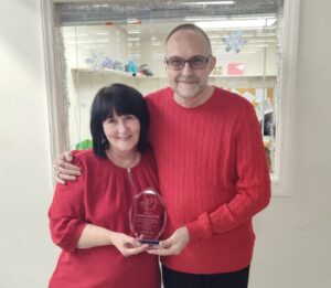 Bobbie poses with Paul Quesenberry holding her plaque