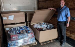 Dale Baker stands next to pallets of donated goods