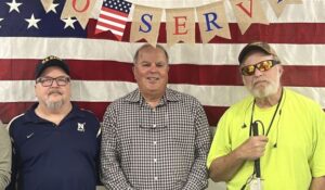 Bobby Ashworth, Tom Serrin and Rick Gaffe pose in front an American flag