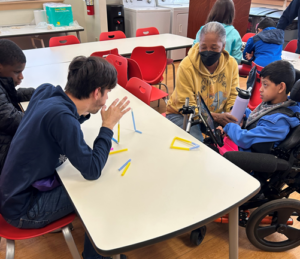 see students build the straw house - with drinking straws