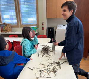 see students build the stick house, witch sticks from outside