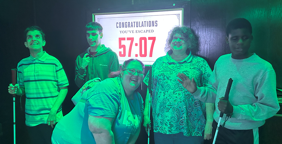 S.E.E. students and leaders pose in front of "congratulations, you escaped 57:07" sign