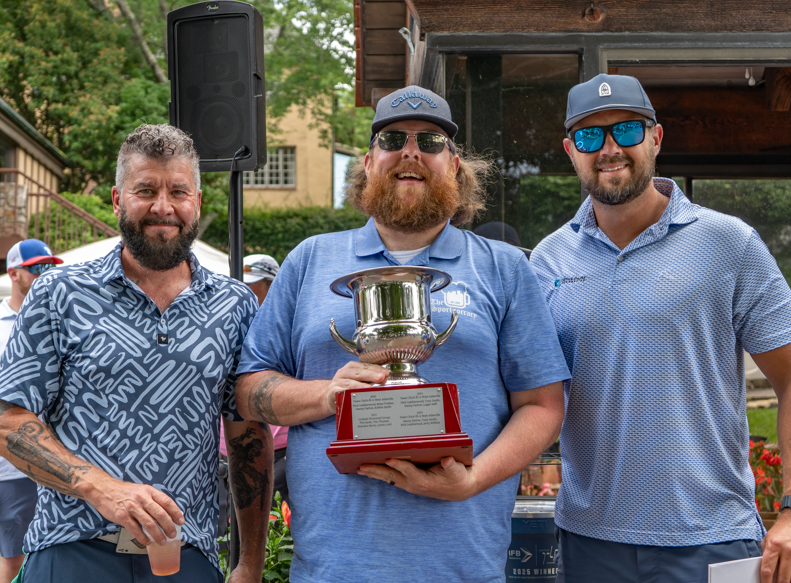 Winning golfers pose with trophy at our 2025 tournament
